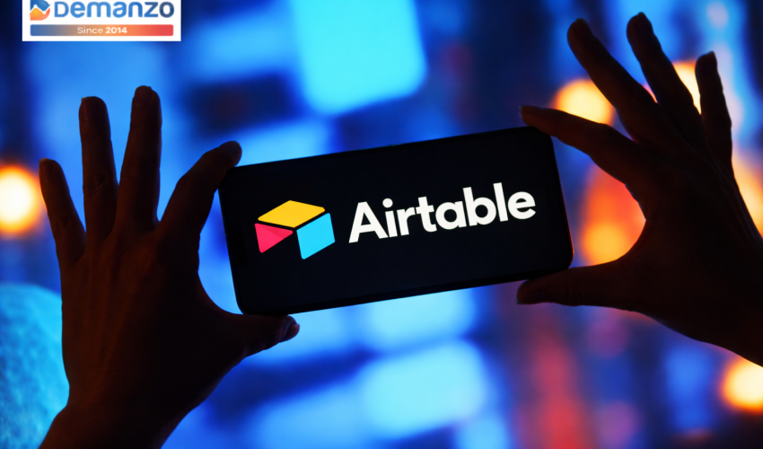 Silhouetted hands holding a phone displaying the Airtable logo, with a colorful blurred background